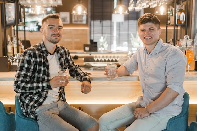 Retrato de dos amigos celebrando con bebida en pub