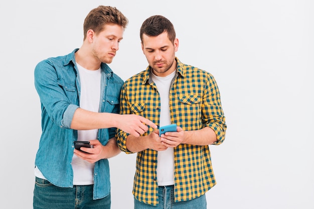 Retrato de dos amigos mirando el teléfono móvil contra el telón de fondo blanco