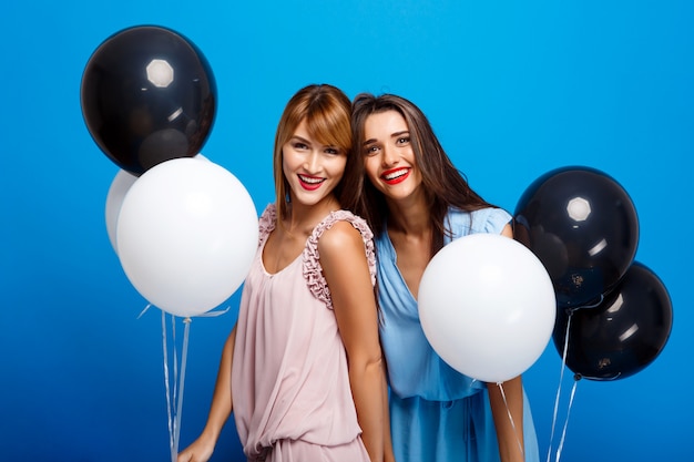 Retrato de dos chicas descansando en la fiesta sobre la pared azul