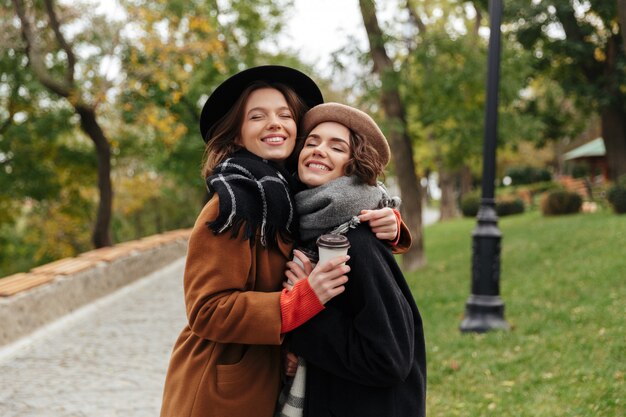 Retrato de dos chicas sonrientes vestidas con ropa de otoño abrazando