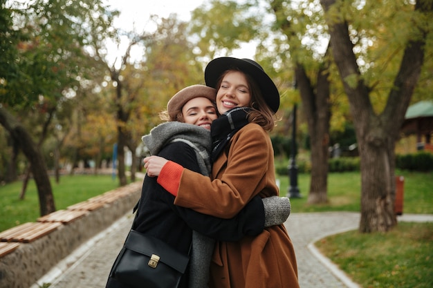 Retrato de dos chicas sonrientes vestidas con ropa de otoño abrazando