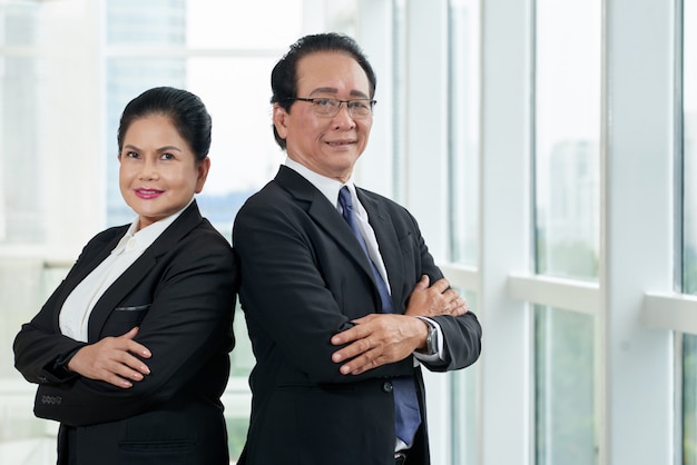 Retrato de dos empresarios de pie de espaldas en la ventana de la oficina