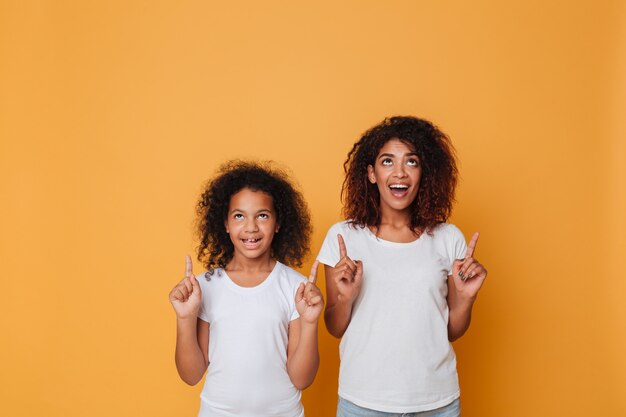 Retrato de dos hermanas afroamericanas alegres señalando con el dedo