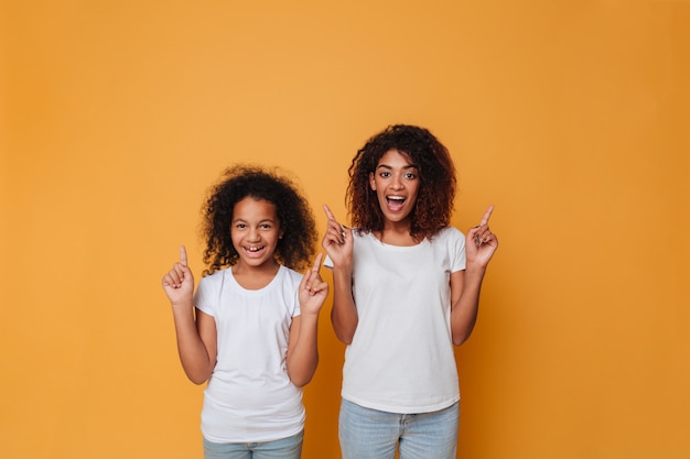 Retrato de dos hermanas afroamericanas alegres señalando con el dedo