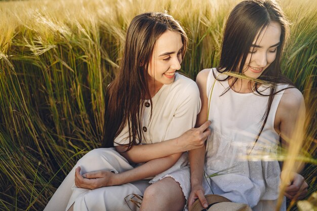 Retrato de dos hermanas en vestidos blancos con pelo largo en un campo