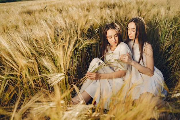 Retrato de dos hermanas en vestidos blancos con pelo largo en un campo