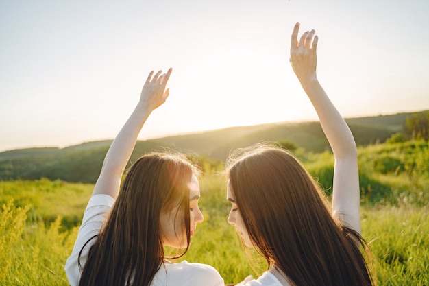 Foto gratuita retrato de dos hermanas en vestidos blancos con pelo largo en un campo