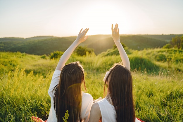 Retrato de dos hermanas en vestidos blancos con pelo largo en un campo