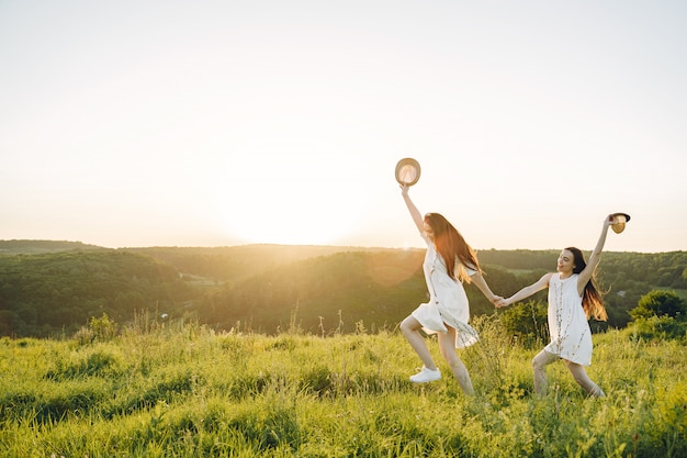 Retrato de dos hermanas en vestidos blancos con pelo largo en un campo