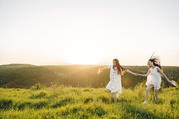 Retrato de dos hermanas en vestidos blancos con pelo largo en un campo