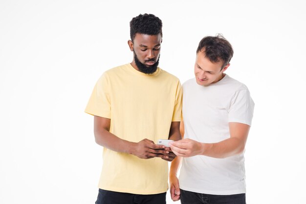 Retrato de dos hombres felices con smartphone aislado sobre pared blanca