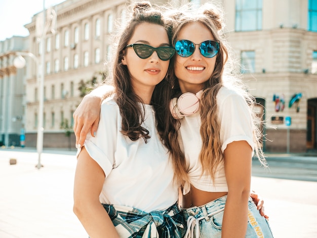 Retrato de dos jóvenes hermosas chicas hipster sonrientes en ropa de camiseta blanca de verano de moda