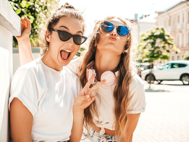 Retrato de dos jóvenes hermosas mujeres hipster sonrientes en ropa de camiseta blanca de verano de moda