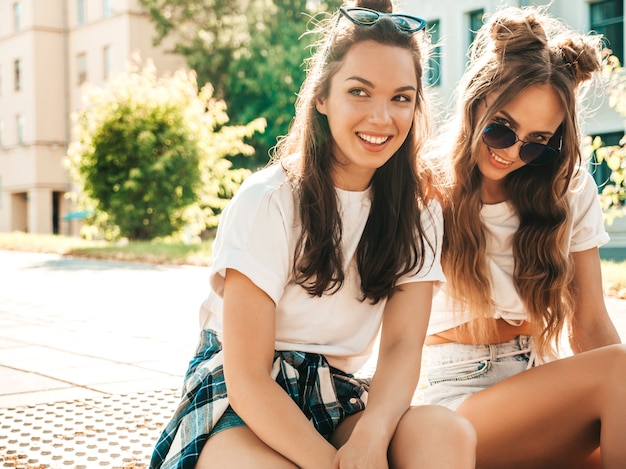 Retrato de dos jóvenes hermosas mujeres hipster sonrientes en ropa de camiseta blanca de verano de moda