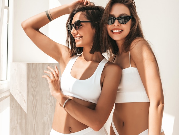 Retrato de dos jóvenes hermosas mujeres sonrientes en lencería blanca