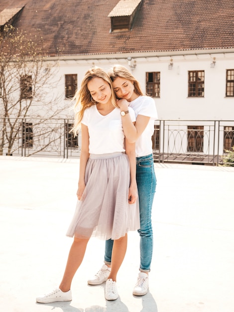 Retrato de dos jóvenes hermosas rubias sonrientes chicas hipster en ropa de moda verano camiseta blanca. . Modelos positivos divirtiéndose.