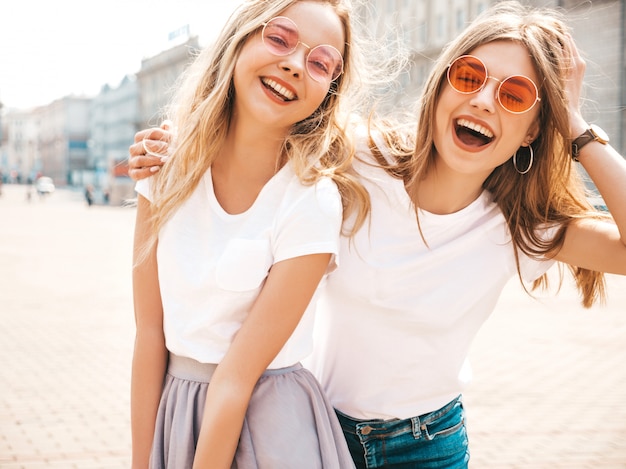 Retrato de dos jóvenes hermosas rubias sonrientes chicas hipster en ropa de moda verano camiseta blanca. .