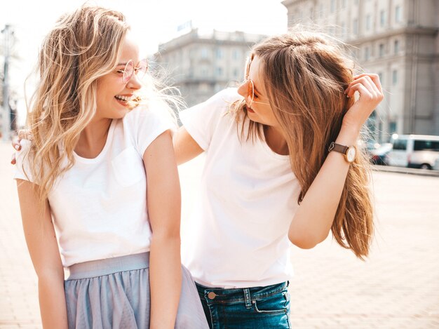 Retrato de dos jóvenes hermosas rubias sonrientes chicas hipster en ropa de moda verano camiseta blanca. .