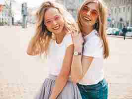 Foto gratuita retrato de dos jóvenes hermosas rubias sonrientes chicas hipster en ropa de moda verano camiseta blanca. .