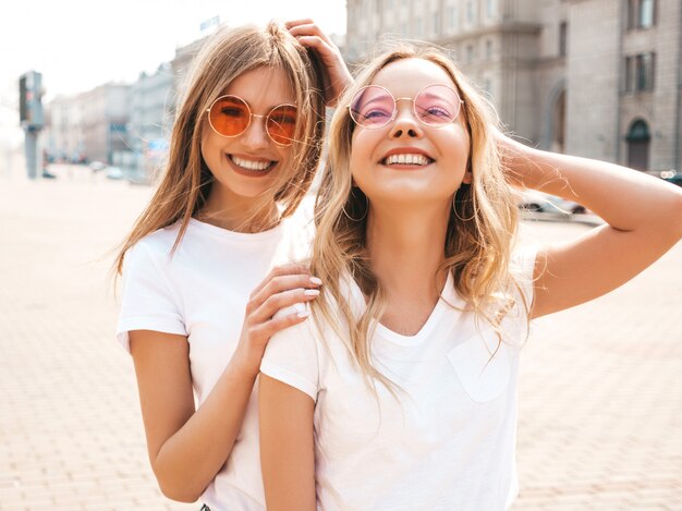 Retrato de dos jóvenes hermosas rubias sonrientes chicas hipster en ropa de moda verano camiseta blanca. .