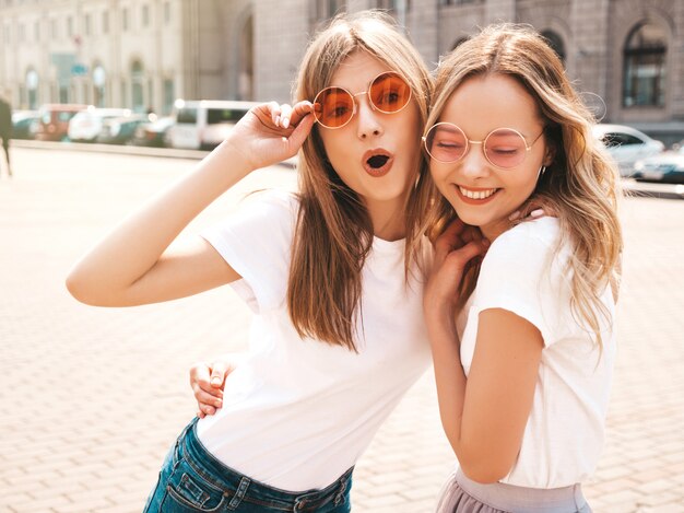 Retrato de dos jóvenes hermosas rubias sonrientes chicas hipster en ropa de moda verano camiseta blanca. .