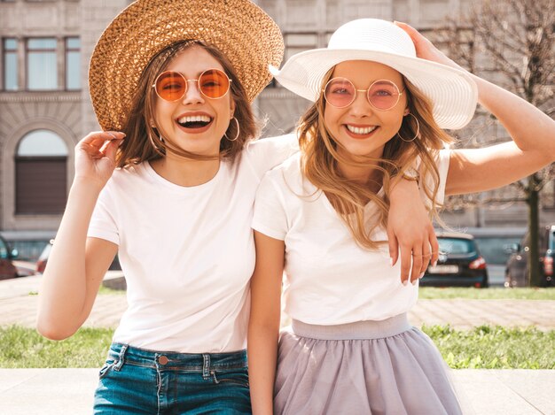 Retrato de dos jóvenes hermosas rubias sonrientes chicas hipster en ropa de moda verano camiseta blanca. .