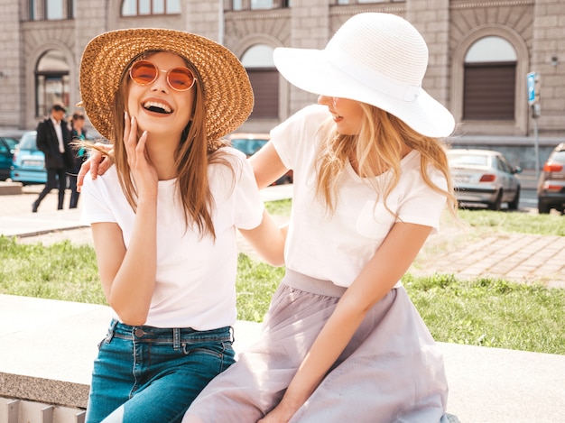 Retrato de dos jóvenes hermosas rubias sonrientes chicas hipster en ropa de moda verano camiseta blanca. .