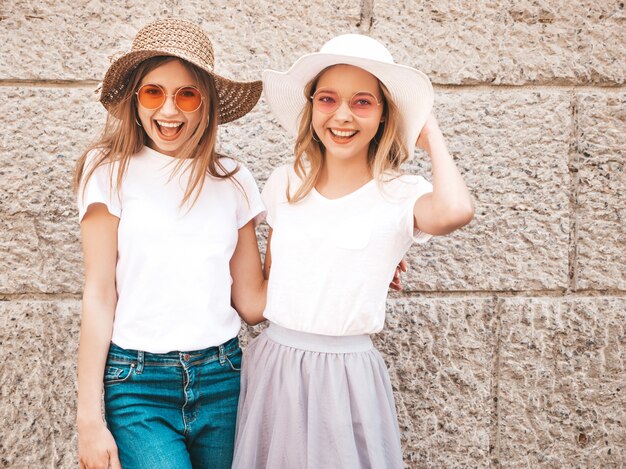 Retrato de dos jóvenes hermosas rubias sonrientes chicas hipster en ropa de moda verano camiseta blanca. .