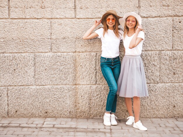 Retrato de dos jóvenes hermosas rubias sonrientes chicas hipster en ropa de moda verano camiseta blanca. .