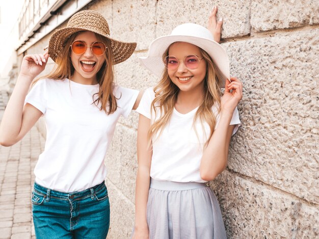 Retrato de dos jóvenes hermosas rubias sonrientes chicas hipster en ropa de moda verano camiseta blanca. .