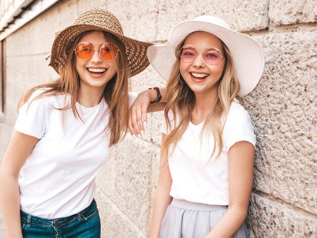 Retrato de dos jóvenes hermosas rubias sonrientes chicas hipster en ropa de moda verano camiseta blanca. .