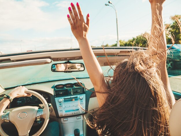 Retrato de dos jóvenes hermosas y sonrientes chicas hipster en coche descapotable