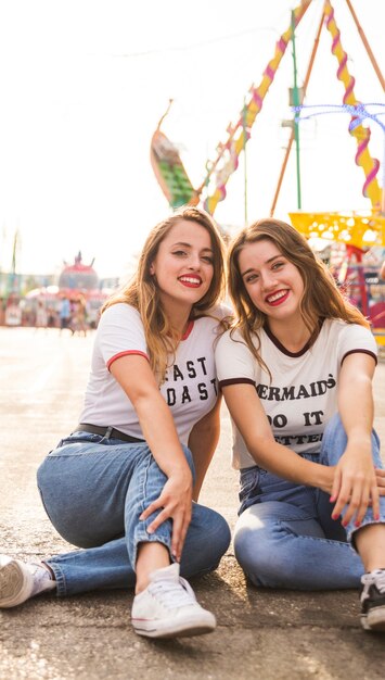 Retrato de dos mujeres felices sentados en el pavimento