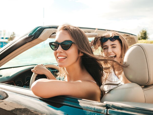 Retrato de dos mujeres hipster hermosa y sonriente joven en coche descapotable