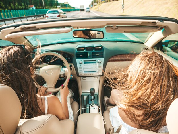 Retrato de dos mujeres hipster hermosa y sonriente joven en coche descapotable