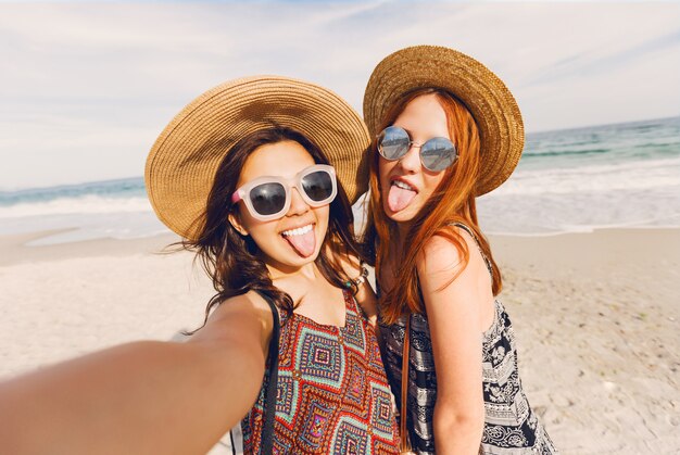 Retrato de dos mujeres jóvenes mejores amigas bastante frescas haciendo autorretrato y divirtiéndose en la playa