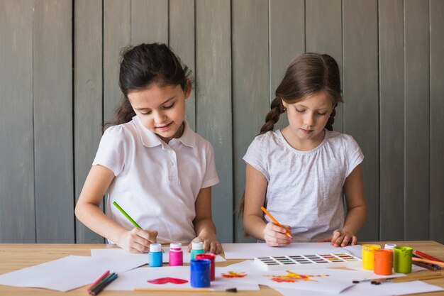 Retrato de dos niñas pintando en el papel blanco sobre el escritorio