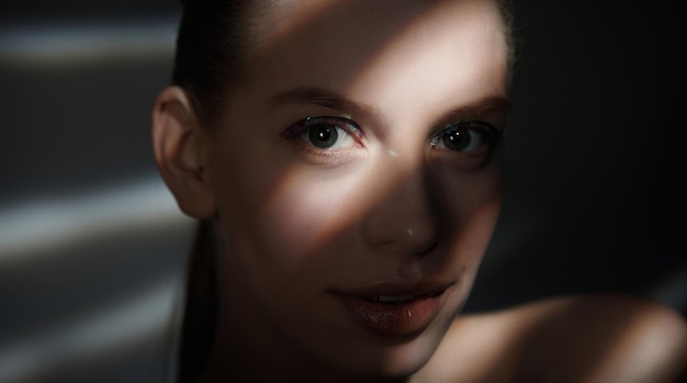 Retrato dramático de mujer con luces y sombras en su rostro.