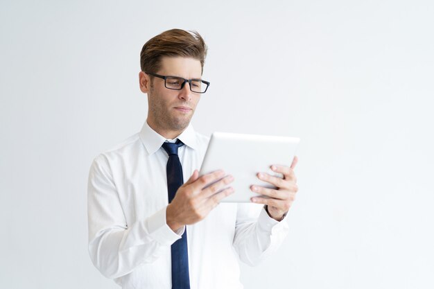 Retrato del ejecutivo joven serio que usa la tableta digital