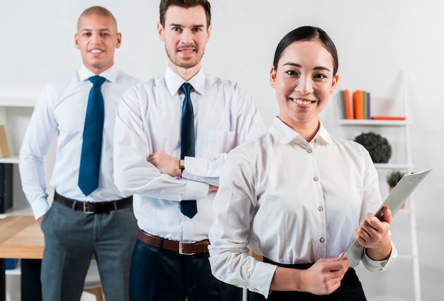 Retrato de una empresaria asiática que sostiene el sujetapapeles en la mano que se coloca delante del hombre de negocios dos