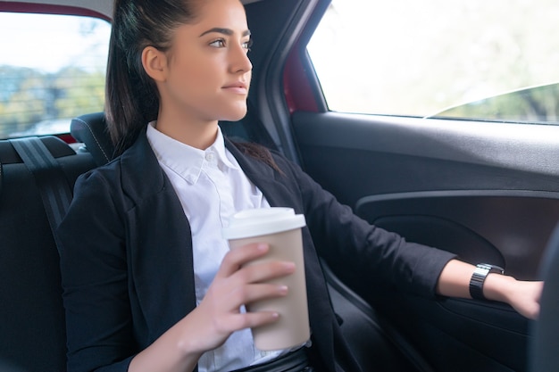 Retrato de empresaria bebiendo café en su camino al trabajo en coche