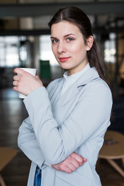 Retrato de la empresaria bonita que sostiene la taza de café