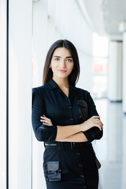 Retrato de la empresaria cruzó las manos en la oficina con ventanas panorámicas.