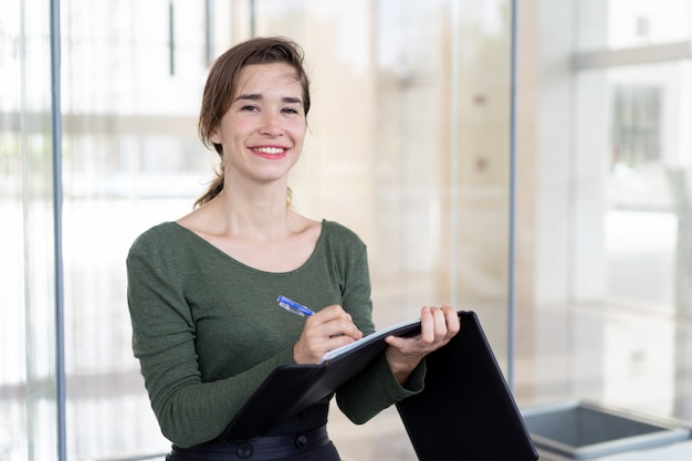 Foto gratuita retrato de la empresaria joven alegre con el cuaderno