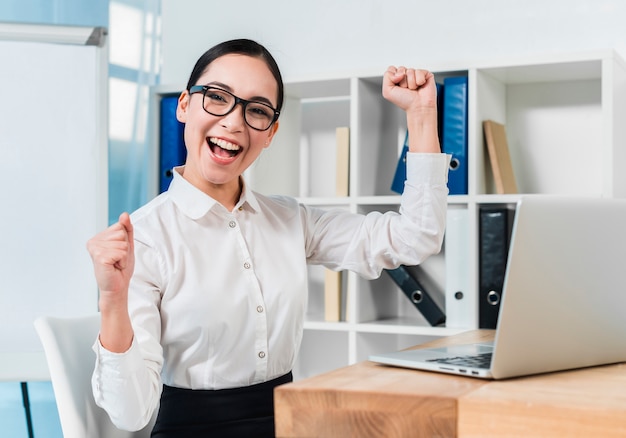 Retrato de una empresaria joven emocionada que anima en el lugar de trabajo