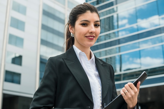 Retrato de una empresaria joven sonriente que se coloca delante del edificio