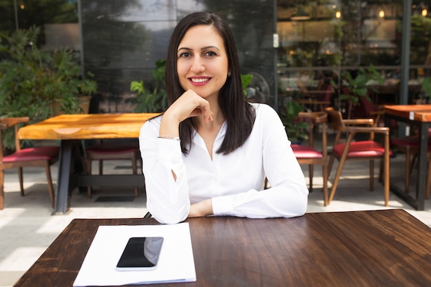 Foto gratuita retrato de la empresaria joven sonriente que se sienta en la tabla