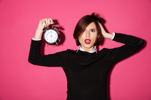 Retrato de una empresaria molesta sorprendida con reloj despertador
