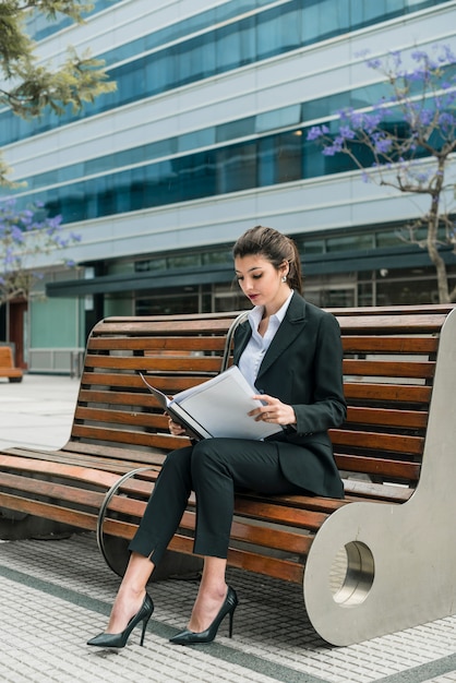 Retrato de una empresaria sentado en la banca leyendo carpeta