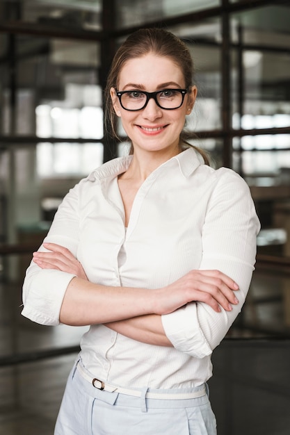 Retrato de empresaria sonriente en interiores con los brazos cerrados